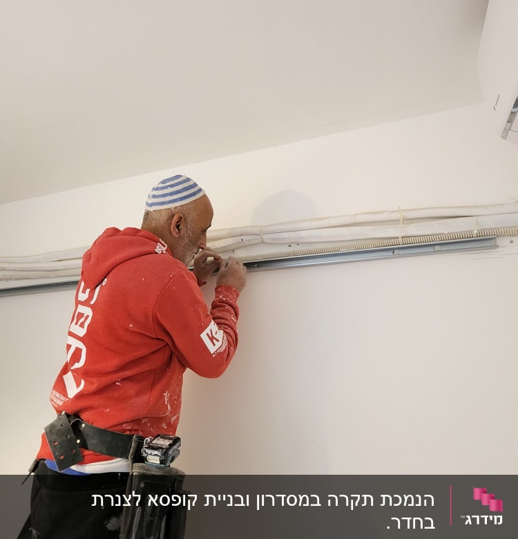 אדם עובד על קיר גבס עם כלי עבודה